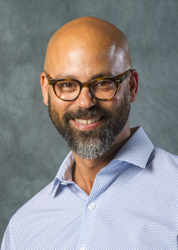 A profile picture of Brett R. Coleman, a man who is smiling, wearing glasses and a blue striped collard shirt. A profile picture of Brett R. Coleman, a man who is smiling, wearing glasses and a blue striped collard shirt.